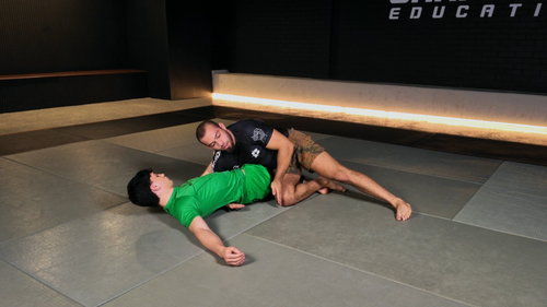 Two individuals practicing martial arts on a mat in a training facility.
